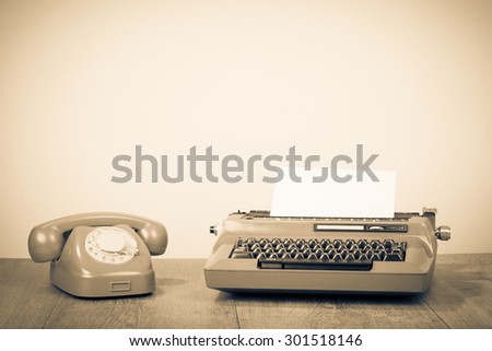 Retro old typewriter and telephone on table. Vintage style sepia photo