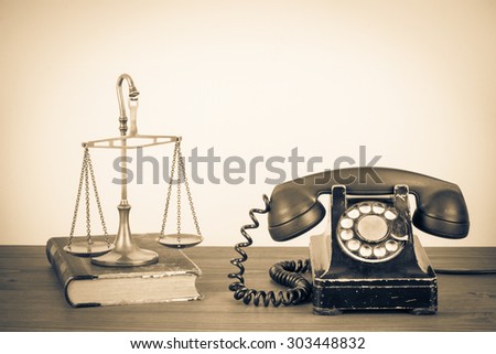 Law scales, old book and retro telephone on table. Vintage style sepia photo