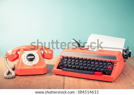 Retro telephone and old typewriter on table front mint green background. Vintage style filtered photo