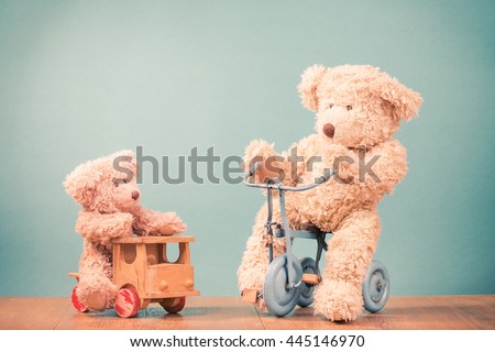 Big and small Teddy Bears on old retro toy bicycle and wooden car. Vintage instagram style filtered photo