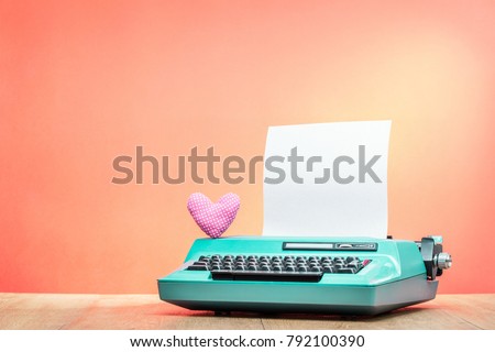 Retro old mint green typewriter with paper sheet and handmade heart shape on wooden desk front gradient background. Valentines day love letter concept. Vintage instagram style filtered photo