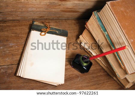 Antique notebook (1940th), ink pen and inkwell, old books on wood background