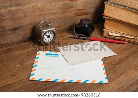 Antique clock, postcard, envelope, ink pen and inkwell, old books on wood background