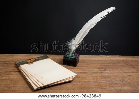 Quill ink pen and inkwell, old notepad on wood table