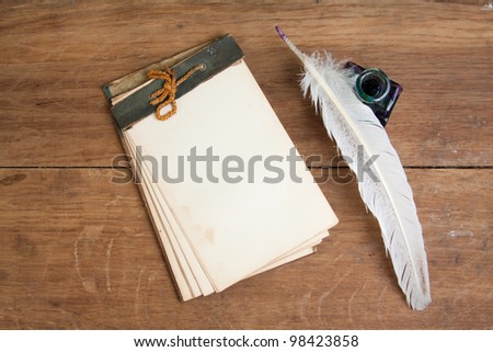 Vintage notebook, quill ink pen and inkwell on wood background