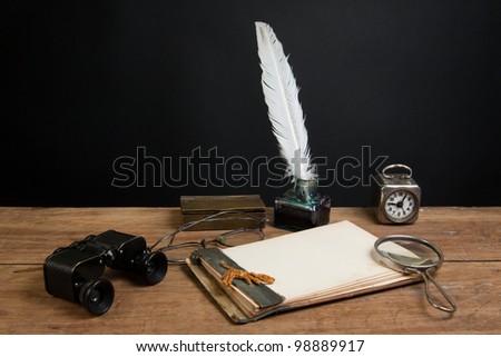 Antique binoculars, quill and inkwell, magnifying glass, old notepad, vintage clock, spectacles on wood table