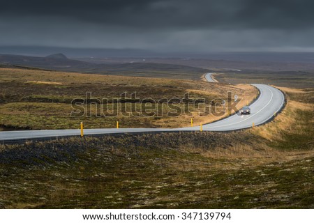 Curve line road with lonely car in Autumn season in cloudy day
