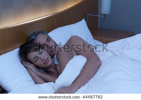 A man and woman cuddle while sleeping peacefully