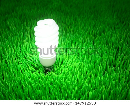 Glowing energy saving light bulb on a green field, energy conservation concept.