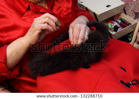 Woman\'s  hands sewing a red coat