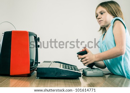 Frustrated little girl on video gaming joystick in front of vintage TV set