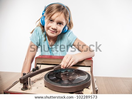 New age little girl meeting vintage sound technology LP record player enjoying music on blue headphones