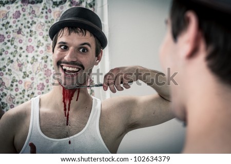Vintage masochist crazy guy slitting throat in mirror while smiling with disturbing glee, white wife beater, hat, and mustache - stock photo