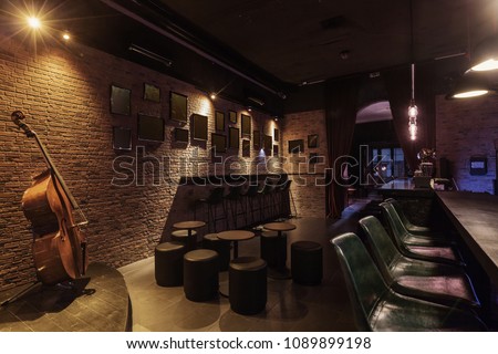 Modern jazz bar interior design, stage with cello, lamps above bar counter