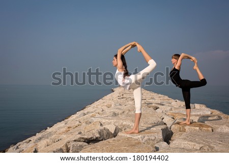 Beautiful young women practicing yoga on the beach. Natarajasana