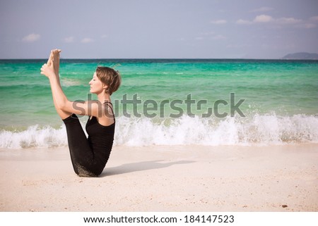 Beautiful woman practicing yoga at seashore. Urdhva mukha paschimottanasana yoga pose