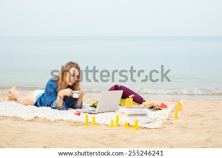 Self employed woman working with laptop on the sea with a cup of coffee