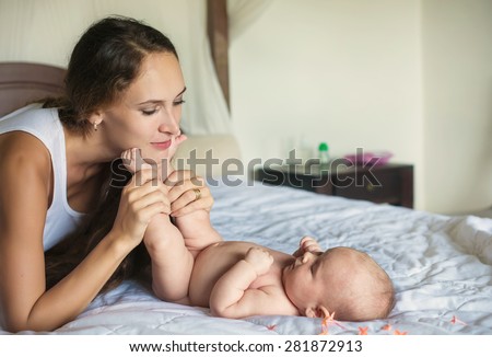 Happy young mother with newborn baby enjoy and relax indoor in bedroom