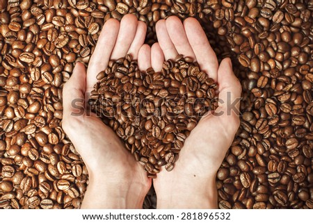 Coffee beans in hands with love heart on coffee bacground