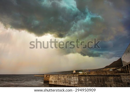 Dark storm clouds and rain over the river and dam
