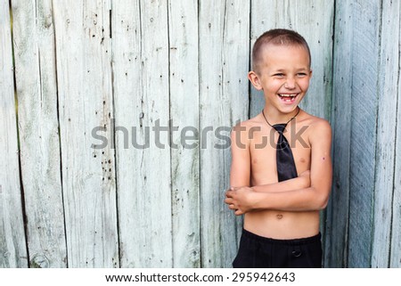 Young Funny Boy smiling toothless in a Business Tie near a wooden fence