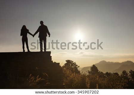 Love couple silhouette looking sunrise in mountains