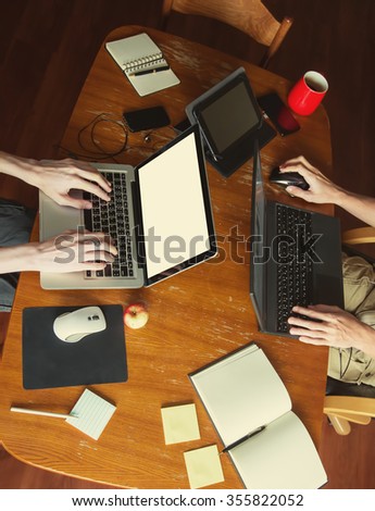 home Workspace. Freelance Family. Teamwork. Desktop table, laptop, tablet, typing keyboard hands, coffee, apple, headphones, smartphones, paper and pen