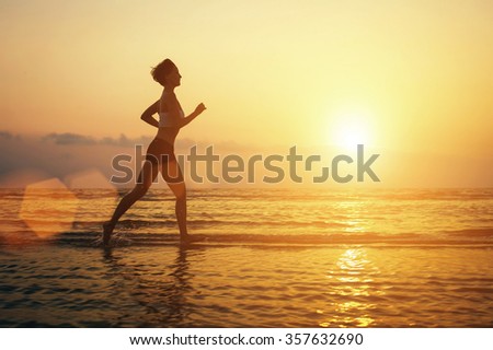 Running woman on the beach sport silhouette. Sunrise, sun reflection on sea water. Freedom, beauty
