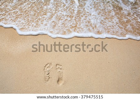 Footprints on sea shore. Sea water wave. Beach Vacation