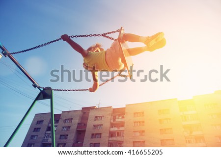 Little girl flying on swing in city house yard. Childhood, Freedom, Happy, Summer Outdoor