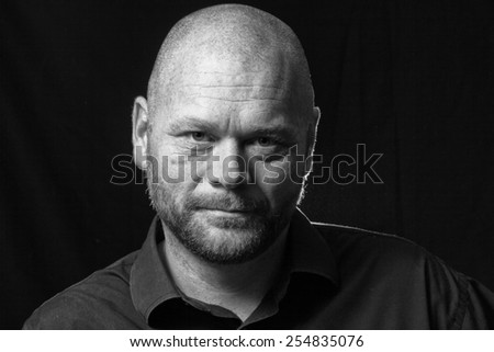 A promotional actor head shot, low key.  Actor looking directly to camera.