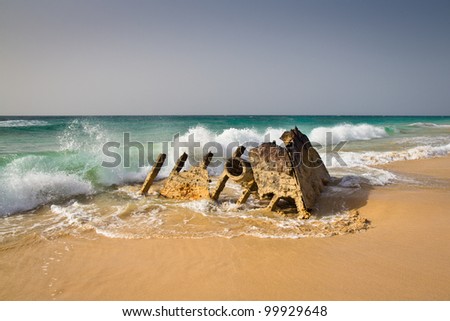 Photograph of a very rusty wreck on a deserted beach on the coast of Africa.