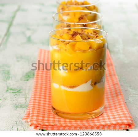 Dessert with mango in a glass on a white table
