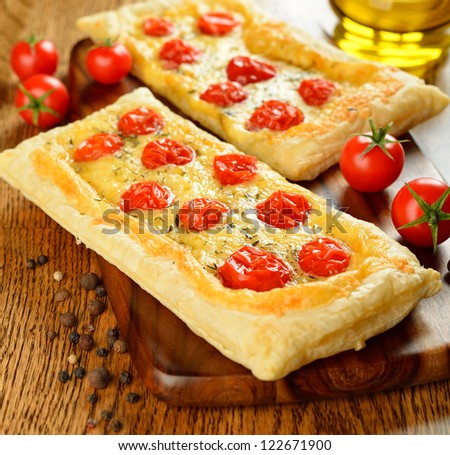 Tart with cheese and cherry tomatoes on a brown table