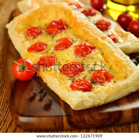 Tart with cheese and cherry tomatoes on a brown table