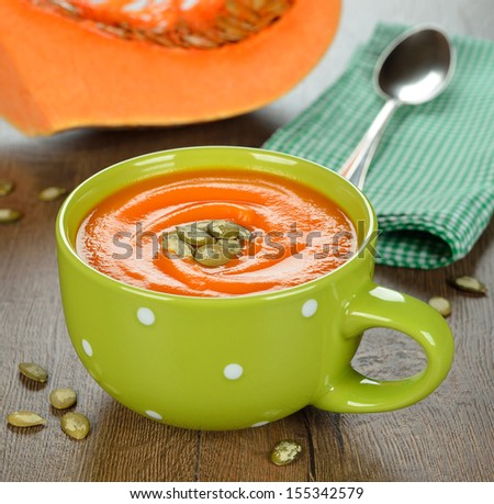 Pumpkin soup in a green bowl on a brown table