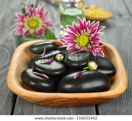 Basalt stones to massage and stone therapy, in a wooden bowl on a gray background
