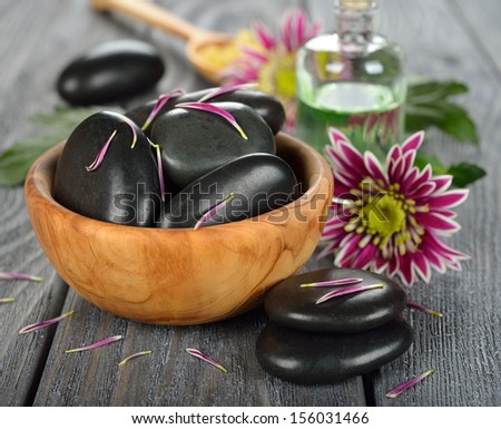 Basalt stones to massage and stone therapy, in a wooden bowl on a gray background