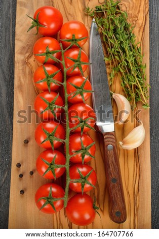 Fresh cherry tomatoes and herbs on a brown board