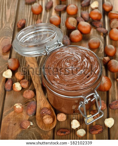 Chocolate paste in a glass jar on a brown background