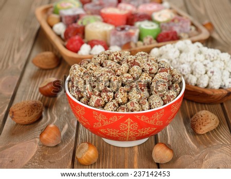 Caramelized peanuts with sesame in a red bowl on a brown background