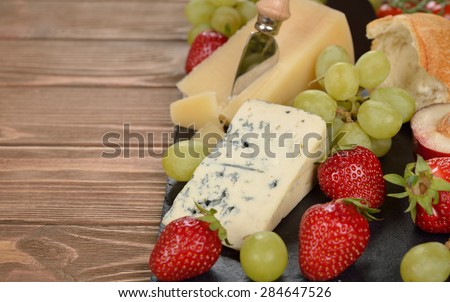 Cheese, grapes and fruit on a brown background