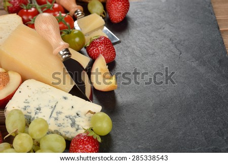 Cheese, grapes and fruit on a black background