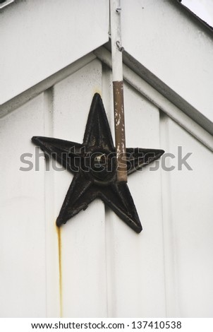 A rusted star on a shed in a back yard garden.