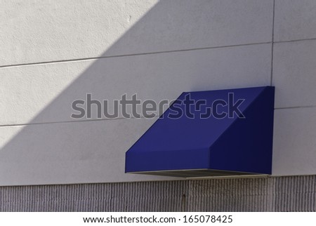 A flue awning in light and shadow on the side of a building.