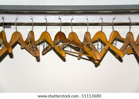 a group of wooden coat hangers on a rack in a public facility.