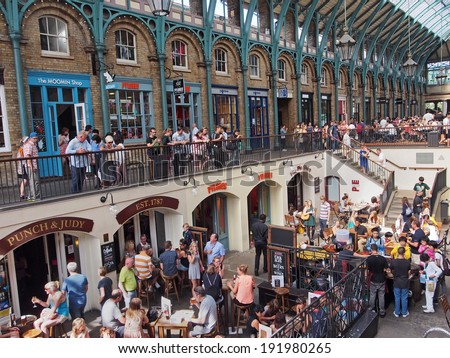 LONDON - AUGUST 4, 2013:  The Covent Gardens market area attracts large crowds of tourists for pubs and shopping on a warm summer day.