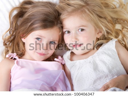 Preschool age girls in bed having a sleep over looking up