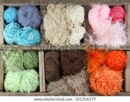 many colorful yarn balls in an aged wooden box