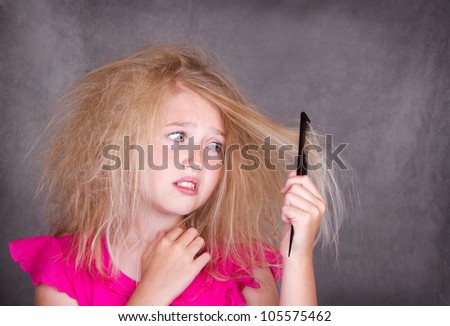 Girl with crazy tangled hair trying to comb it out